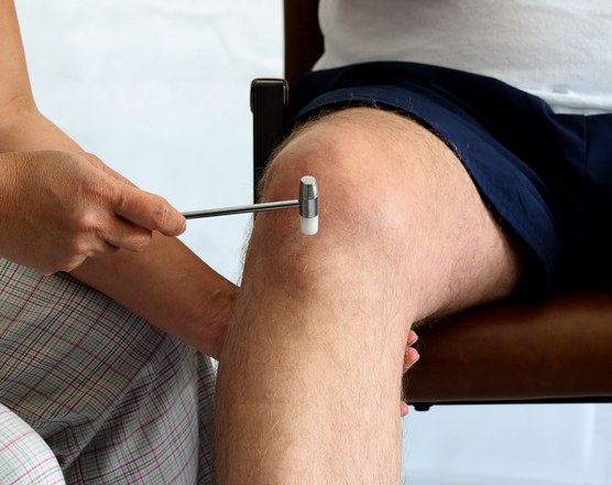 A clinician testing a child's knee reflex with a reflex hammer