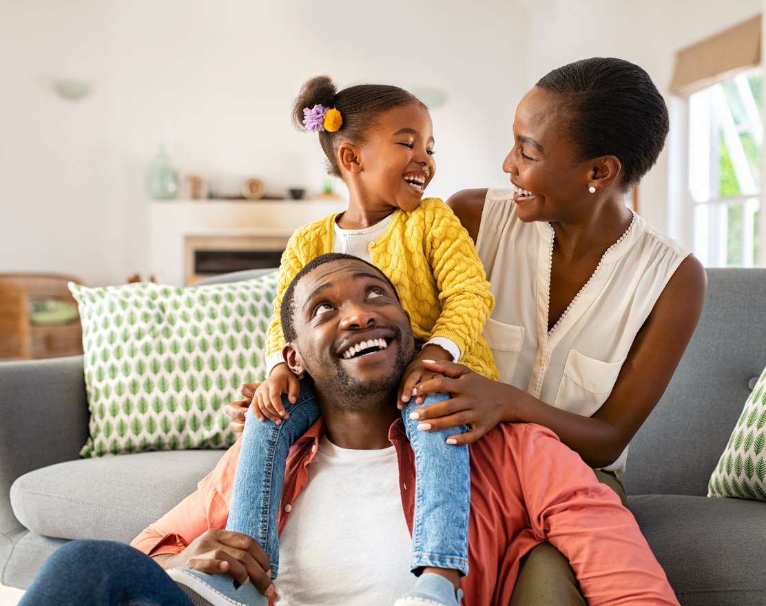 A family sitting together on a sofa in their living room, laughing