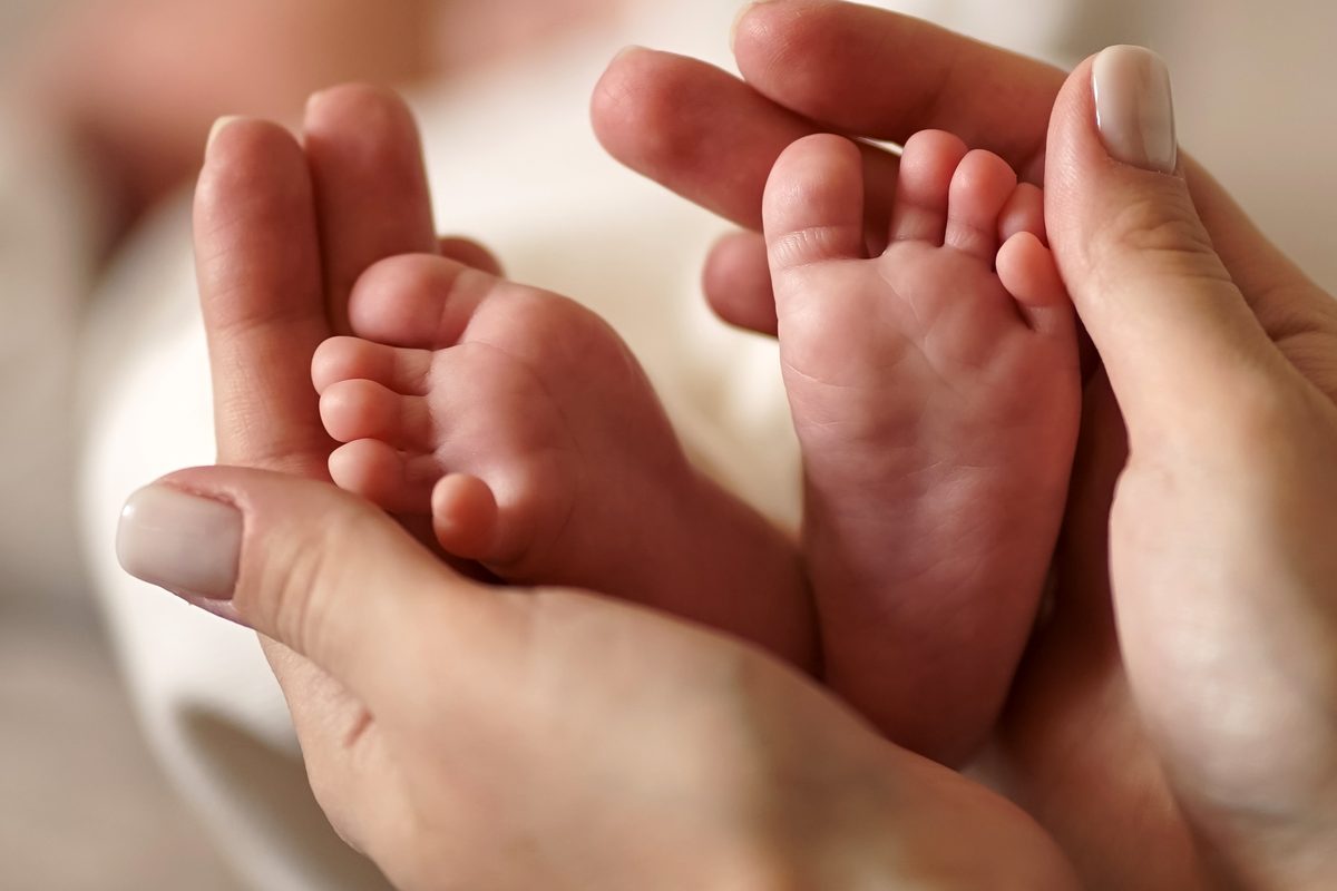 A parent’s hands cradling a baby’s bare feet